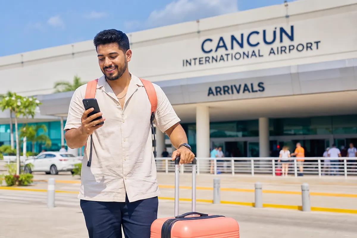 Voyageur souriant regardant son téléphone devant le hall d'arrivée d'un aéroport international