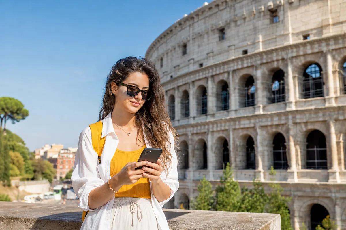Voyageuse en lunettes de soleil consultant son smartphone devant un amphithéâtre antique