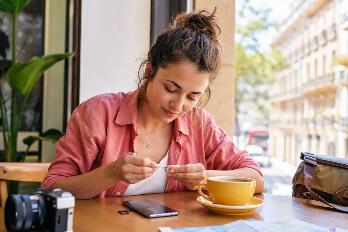 Traveler cleaning the gold contacts of a SIM card with a cotton swab.