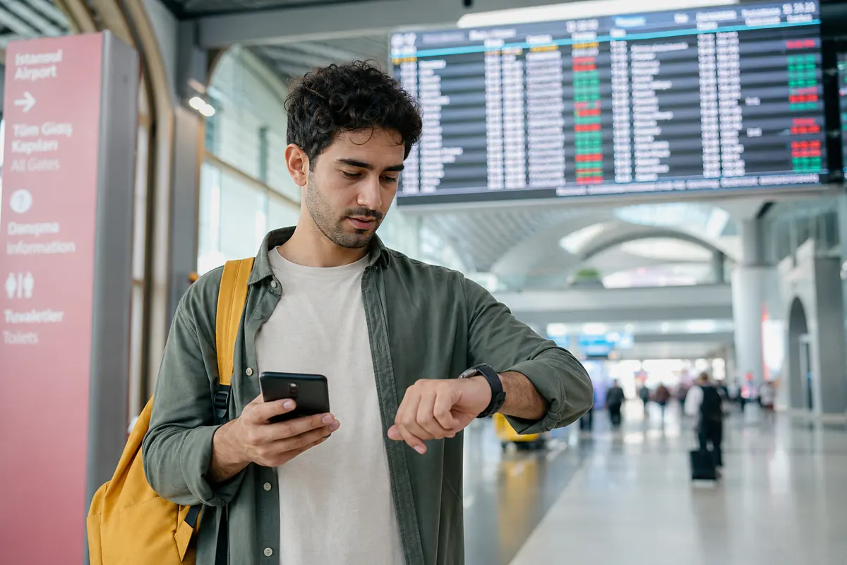 Voyageur pressé utilisant son smartphone à l'aéroport d'Istanbul pendant une escale.