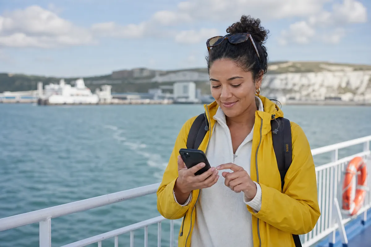 Voyageur sur un ferry activant sa connexion eSIM sur son smartphone.