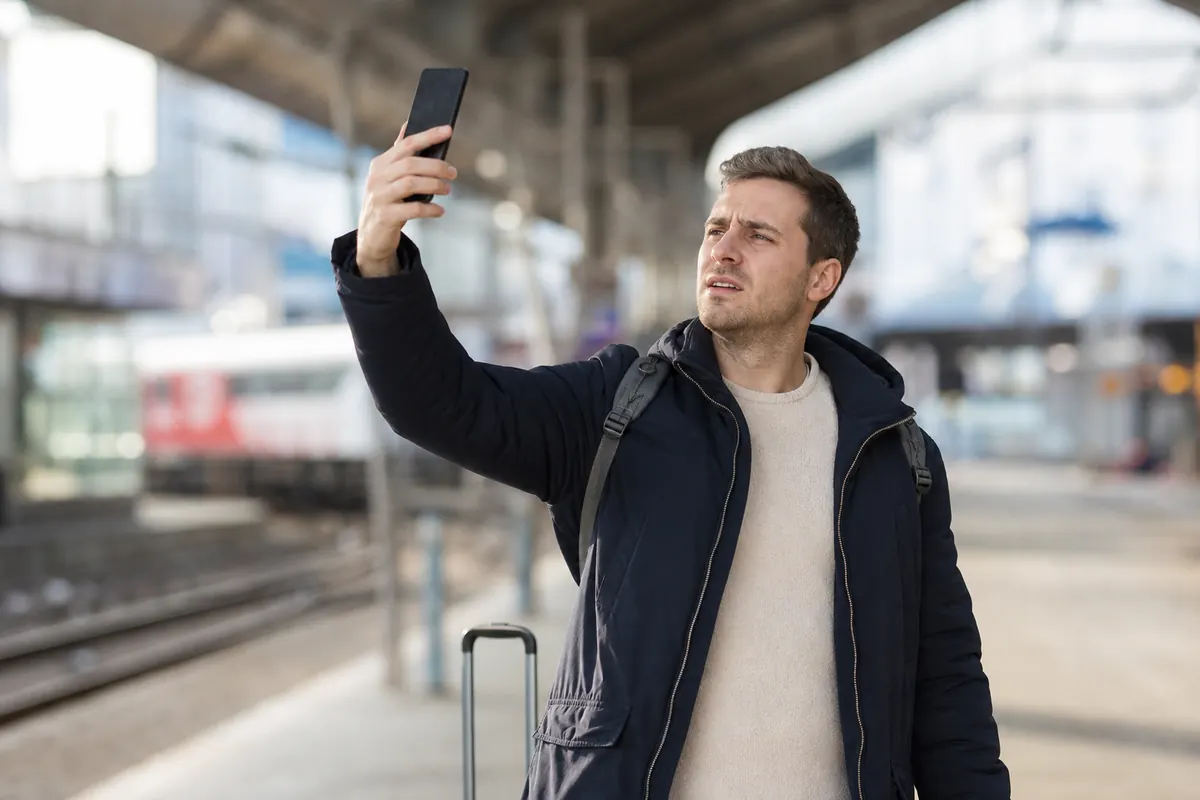 Jeune voyageur configurant le réseau mobile de son iPhone en ville.