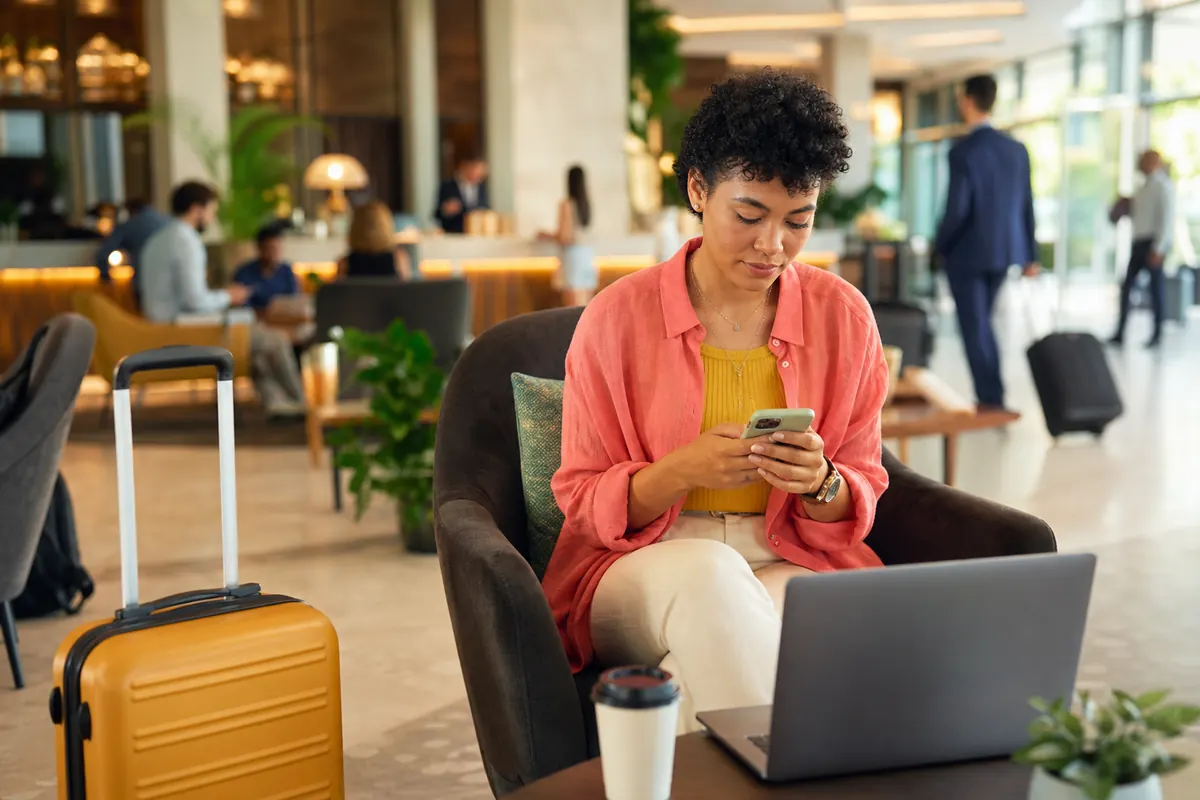Voyageur travaillant sur son smartphone connecté au Wi-Fi public de l'hôtel